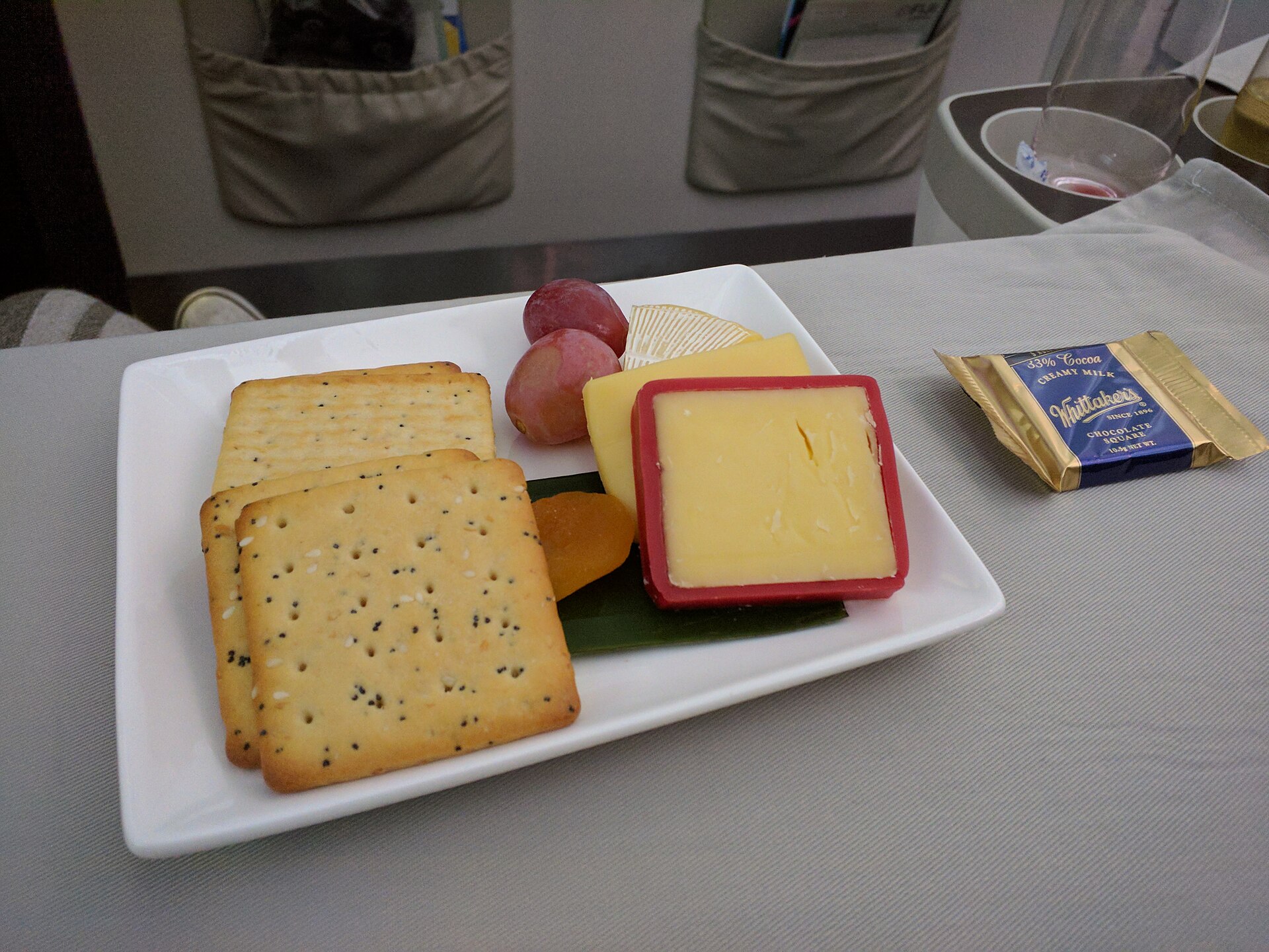 Plateau de fromages d'un repas en classe affaires sur le vol 910 de Fiji Airways de Sydney à Nadi, composé de Camembert, cheddar et Edam, accompagné de raisins rouges, d'abricots secs, de crackers et de chocolat.